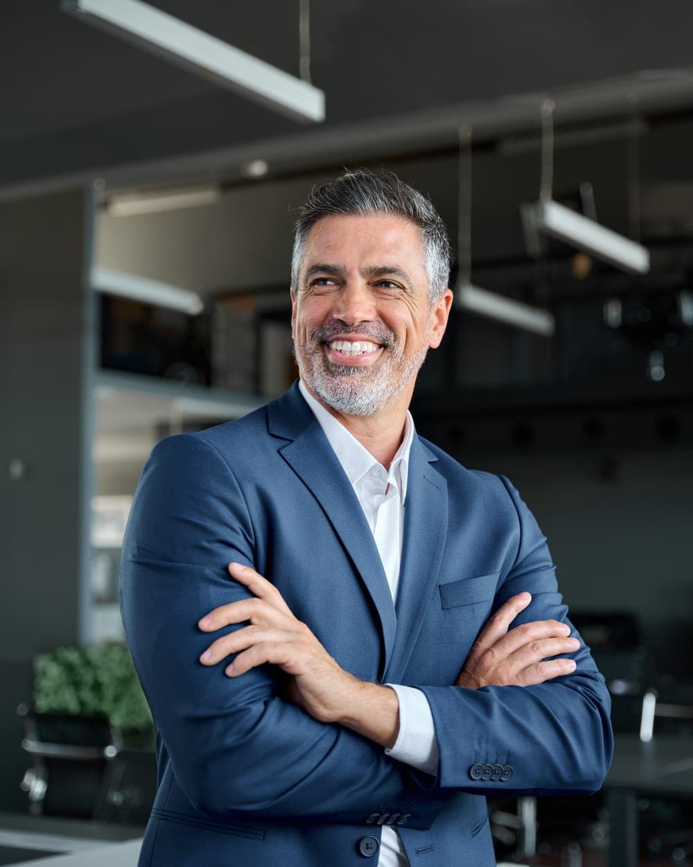 A business owner in a modern office, arms folded, smiling.